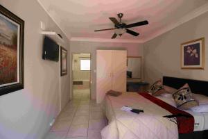 a bedroom with a bed and a ceiling fan at Acacia Grove Guest House in Johannesburg +21 photos