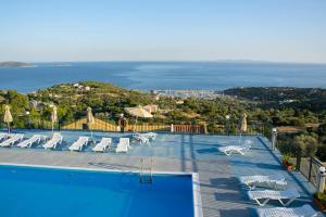 a pool with chairs and a view of the ocean at Saint Catherine Hotel in Pythagoreio