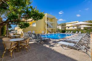 a patio with tables and chairs next to a swimming pool at Apartamentos Don Miguel in Port de Pollensa