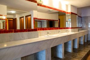 a public bathroom with four sinks and mirrors at Saint Catherine Hotel in Pythagoreio