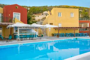a pool with chairs tables and umbrellas and buildings at Saint Catherine Hotel in Pythagoreio