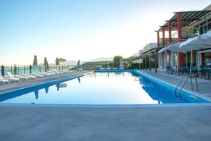 a large swimming pool with lounge chairs and a building at Saint Catherine Hotel in Pythagoreio