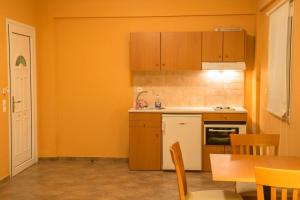 a kitchen with orange walls and wooden cabinets and a table at Saint Catherine Hotel in Pythagoreio