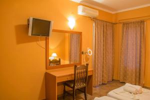 a room with a desk with a mirror and a television at Saint Catherine Hotel in Pythagoreio