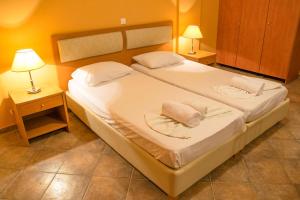 a bedroom with a large white bed with two lamps at Saint Catherine Hotel in Pythagoreio