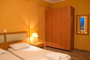 a bedroom with two beds and a wooden cabinet at Saint Catherine Hotel in Pythagoreio
