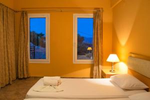a bedroom with a bed and two windows at Saint Catherine Hotel in Pythagoreio