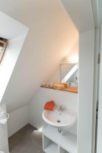 ein weißes Badezimmer mit einem Waschbecken und einem Spiegel in der Unterkunft Refugium Lübeck in Lübeck