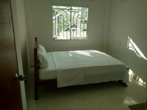 Bett in einem Zimmer mit Fenster in der Unterkunft Apartamento en Taganga in Taganga