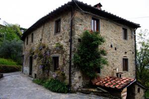 an old stone house with a tree at La Balconata in Bagni di Lucca