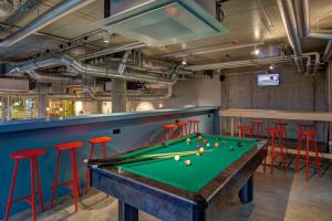 a pool table in a bar with red stools at MEININGER Hotel Berlin East Side Gallery in Berlin