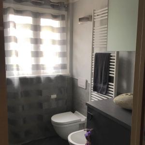 uma casa de banho com um WC, um lavatório e uma janela em A casa di Romeo em Madesimo