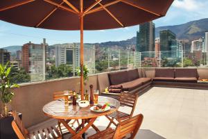 una mesa y sillas en un balcón con sombrilla en Sites Hotel, en Medellín