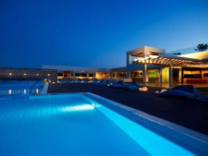 a swimming pool in front of a building at night at Thalatta Seaside Hotel in Agia Anna