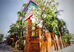 a fence with trees and plants in front of a house at Kaya Place in Bangkok