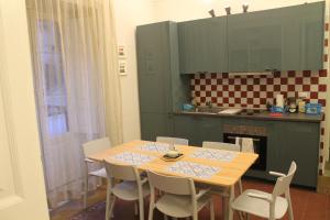 kuchnia z drewnianym stołem i białymi krzesłami w obiekcie Ursino rooms apartment w Katanii