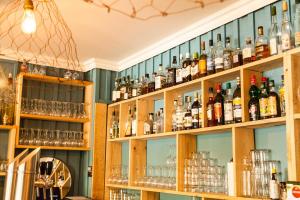 a bar with shelves filled with bottles and glasses at Hôtel Le Caillebotis in Cap-Ferret