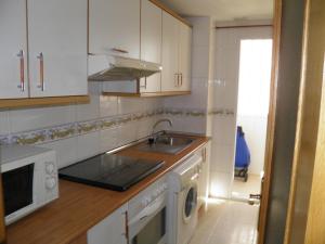 een witte keuken met een wastafel en een fornuis bij BEFERENT Bulevar Playa San Juan in Alicante