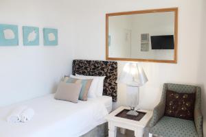 1 dormitorio con cama, silla y espejo en Oceans Hotel & Self Catering, en Mossel Bay