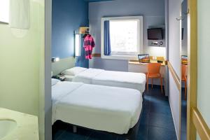 a room with two beds and a desk with a window at ibis budget Belem in Belém