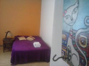 Dormitorio con cama morada y pintura en la pared en Departamento Fran en La Plata
