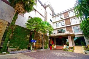 a building with a palm tree in front of it at Eurna Resort Hotel in Bangkok