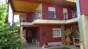 una casa roja con un balcón en el lateral. en Hosteria Kaiken Gregores, en Gobernador Gregores