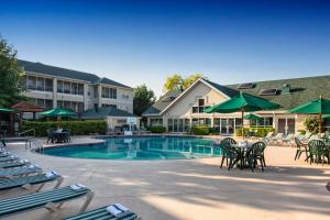 a resort pool with chairs and tables and green umbrellas at Palace View Resort by Spinnaker in Branson