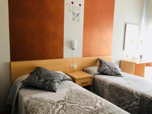 a bedroom with two beds and a nightstand between them at Hotel Viñas 17 in Teruel