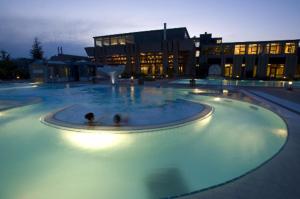 two people in a swimming pool in a building at La Clé des Champs in Les Fourgs
