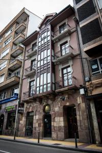 un edificio rosa con balcones en una calle de la ciudad en Cuatro Caminos Rooms, en Torrelavega