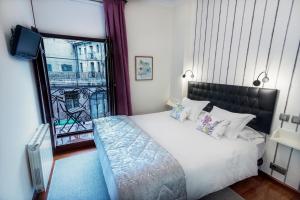 a bedroom with a large bed and a balcony at Cuatro Caminos Rooms in Torrelavega
