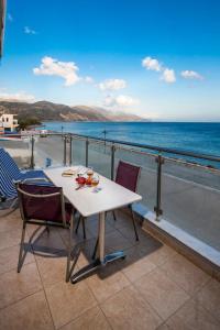 stół i krzesła na balkonie z widokiem na ocean w obiekcie Paleochora Apartments w mieście Palaiochóra