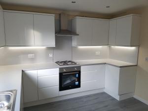 a kitchen with white cabinets and a stove top oven at Linlithgow Loch Apartment in Linlithgow