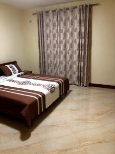 een slaapkamer met een bed en een raam met gordijnen bij Kigali Village Suites in Kigali