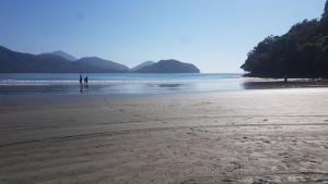 two people standing on a beach near the water at Suites Nativa in Ubatuba
