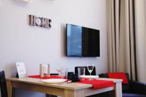 Apartment III GrayFor2 Old Town Kraków في كراكوف: طاولة مع كؤوس للنبيذ وتلفزيون على الحائط