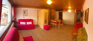 sala de estar con muebles de color rojo y mesa en Residenza Grazia, en Madonna di Campiglio