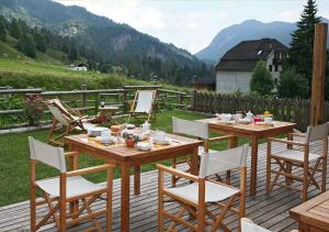 a wooden table and chairs on a wooden deck at Hotel Garni Plueme in Sauris