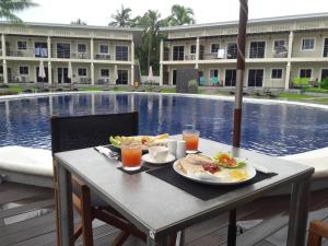 a table with breakfast food and drinks next to a pool at Malinawon Resort in Panglao Island