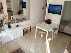 Sala de estar con 2 mesas blancas y TV en Carihuela Sun Beach, en Torremolinos