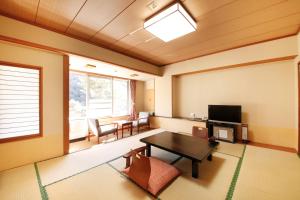 a living room with a table and a tv at Shimobe Hotel in Minobu