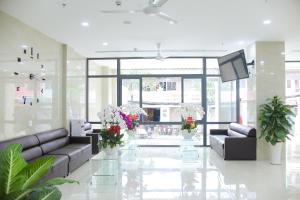 a lobby with couches and a television and flowers at SoLex Hotel in Ho Chi Minh City