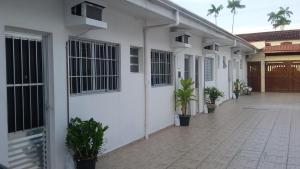 a white house with potted plants and a courtyard at Suítes Eu in Caraguatatuba