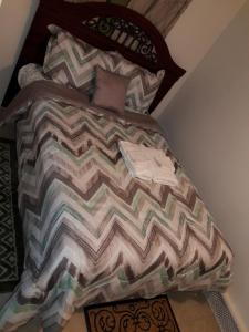 a bed with a comforter and pillows on it at Studio, One and Two Bedroom Apartments - Bronx in Bronx
