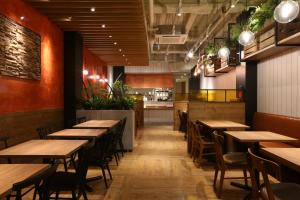 名古屋市にあるホテル ウィング インターナショナル セレクト 名古屋 栄の木製のテーブルと椅子、キッチンが備わるレストラン