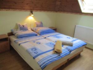 1 dormitorio con 1 cama con sábanas azules y blancas en Tavi Vendégház, en Szentgotthárd
