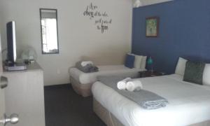 a hotel room with two beds and a television at Woodlands Motel in Kerikeri