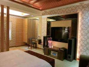 a hotel room with a bed and a flat screen tv at Mambo Impression Motel in Chaozhou