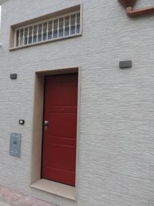una porta rossa sul lato di un edificio di La Casetta a Leporano